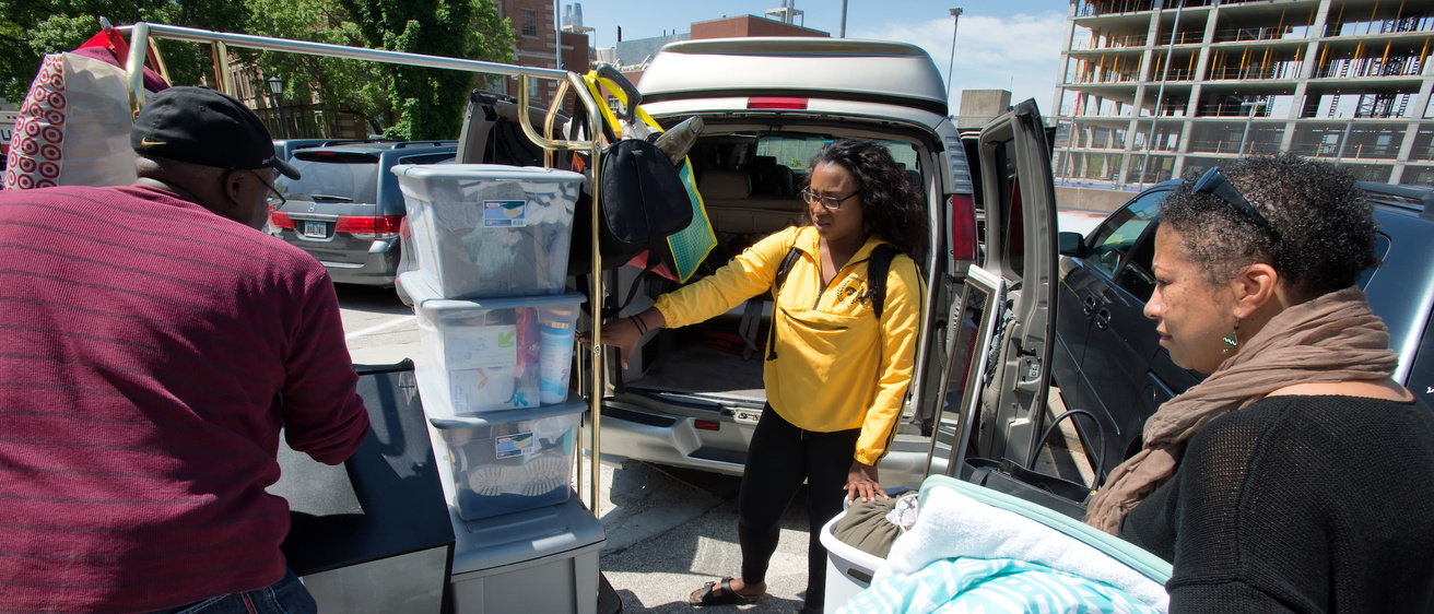 parents and student moving items from car